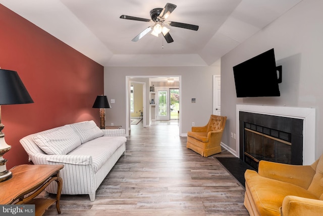 13 Deerfield Ln, Rehoboth Beach, DE 19971 - living room featuring a raised ceiling, a fireplace with flush hearth, a ceiling fan, wood finished floors, and baseboards