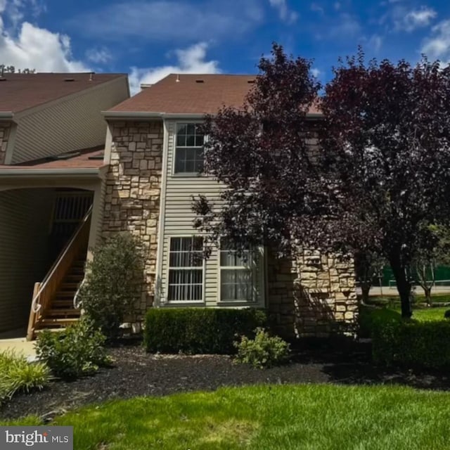view of property exterior featuring stone siding and stairway