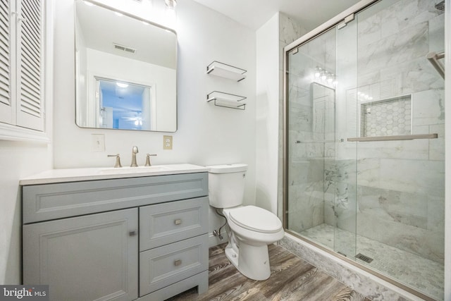 bathroom with wood finished floors, toilet, vanity, and a shower stall