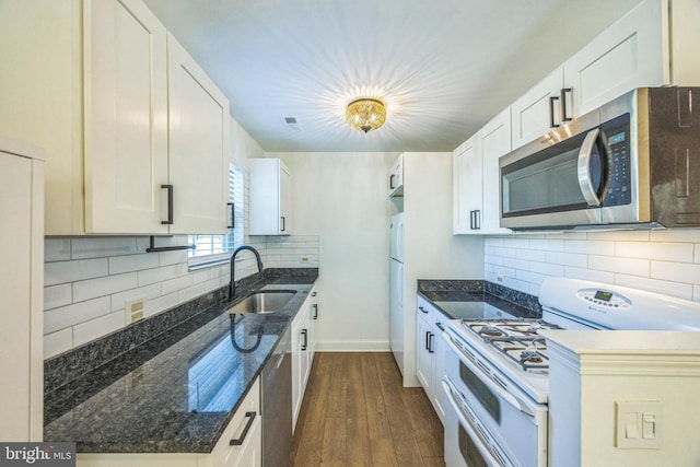 kitchen featuring appliances with stainless steel finishes, a sink, dark wood-type flooring, and decorative backsplash