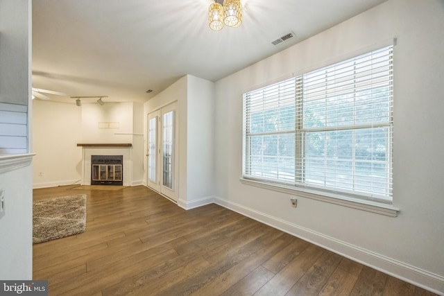 unfurnished living room featuring a fireplace with flush hearth, hardwood / wood-style floors, baseboards, and a chandelier