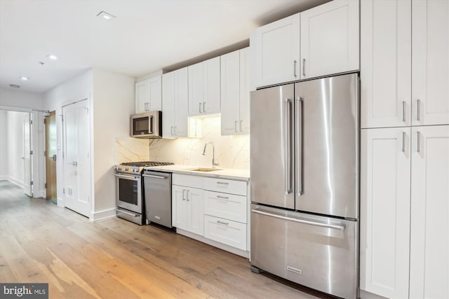 5110 Fort Totten Dr NE Unit P4, Washington, DC 20011 - kitchen with appliances with stainless steel finishes, light wood finished floors, a sink, white cabinets, and tasteful backsplash