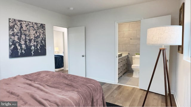 8802 Ashford Rd, Parkville, MD 21234 - bedroom featuring light wood-style flooring, connected bathroom, and tile walls