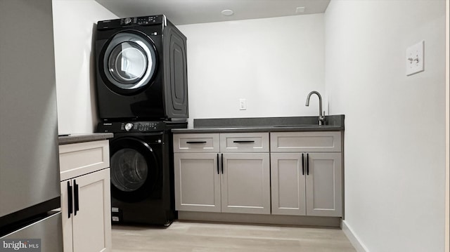 8802 Ashford Rd, Parkville, MD 21234 - clothes washing area with stacked washing machine and dryer, cabinet space, light wood-type flooring, bar with sink, and baseboards