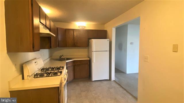 155 Sussex Pl Unit 1522, Absecon, NJ 08205 - kitchen featuring white appliances, under cabinet range hood, a sink, and light countertops