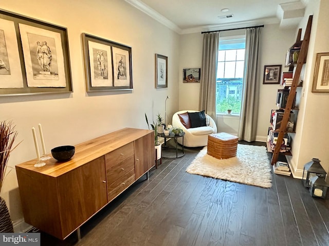 sitting room featuring dark wood-style floors, crown molding, and baseboards