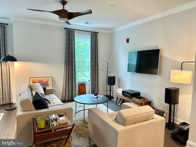 living area featuring wood finished floors, ornamental molding, a ceiling fan, and baseboards