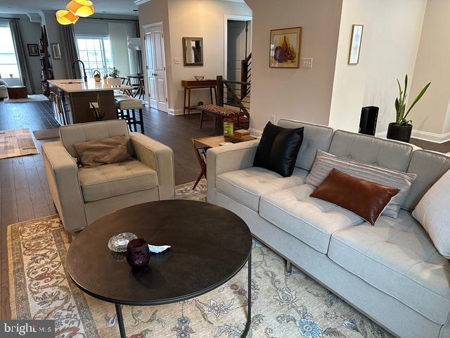living area with dark wood-style floors, baseboards, and stairs