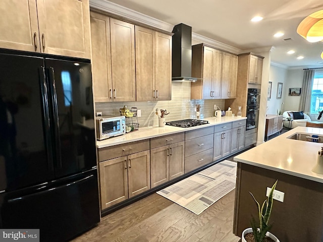 kitchen featuring black appliances, crown molding, wall chimney range hood, a sink, and decorative backsplash