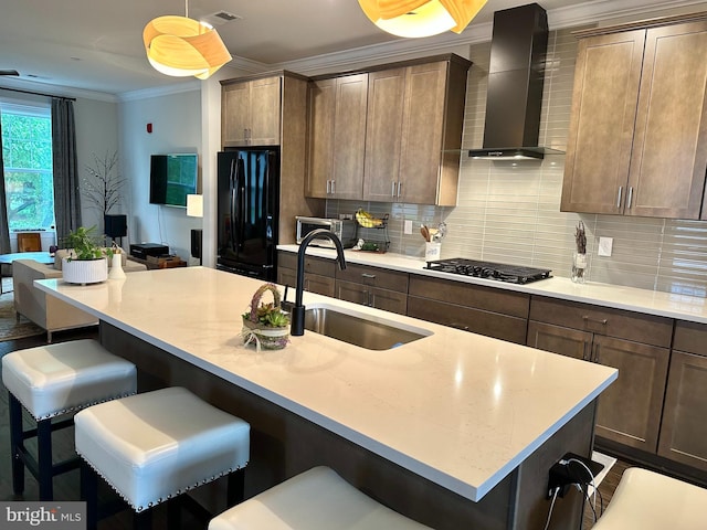 kitchen with black appliances, a sink, wall chimney exhaust hood, ornamental molding, and tasteful backsplash