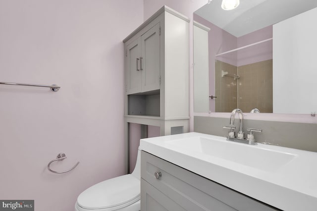full bath with a tile shower, toilet, and vanity