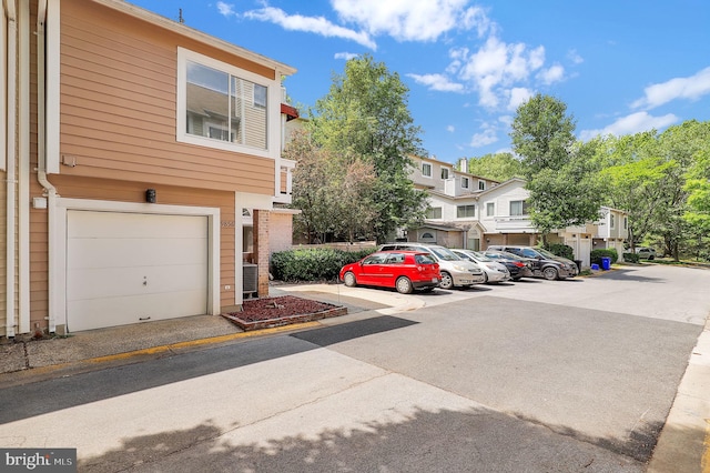 uncovered parking lot featuring a residential view and a garage