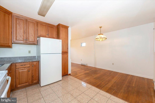 1426 W 11th St, Frederick, MD 21702 - kitchen featuring freestanding refrigerator, brown cabinets, range, light tile patterned floors, and decorative light fixtures