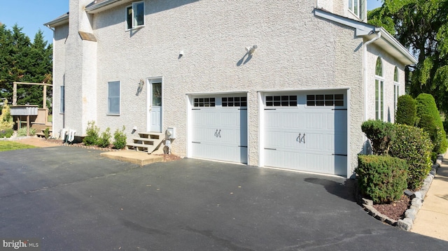 123 Nantucket Dr, Middletown, DE 19709 - view of side of property featuring a chimney, driveway, stucco siding, and a garage