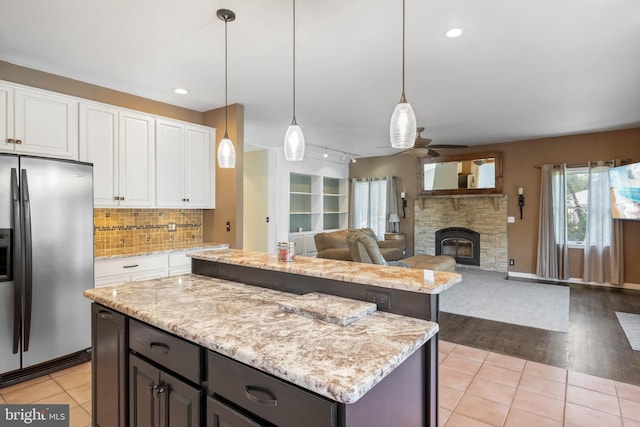 123 Nantucket Dr, Middletown, DE 19709 - kitchen featuring stainless steel refrigerator with ice dispenser, a center island, ceiling fan, a stone fireplace, and white cabinets