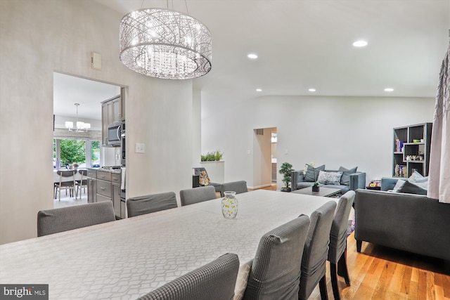 dining area with a chandelier, light wood-style floors, recessed lighting, and lofted ceiling