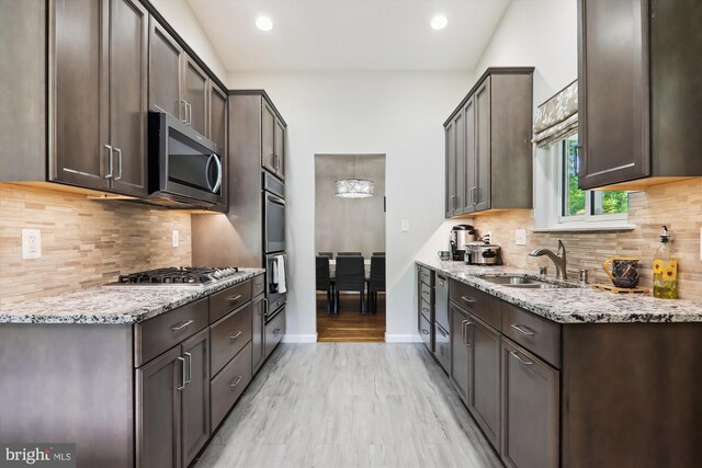 kitchen with a sink, appliances with stainless steel finishes, dark brown cabinetry, decorative backsplash, and recessed lighting
