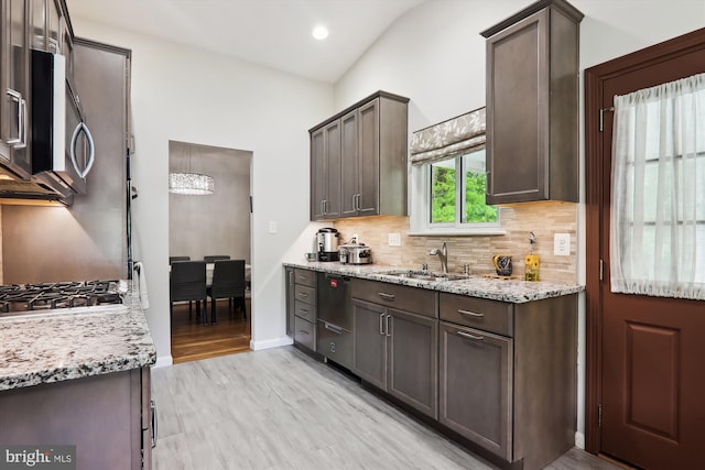 kitchen with a sink, dark brown cabinetry, decorative backsplash, stainless steel microwave, and light stone counters