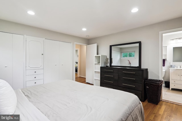 bedroom with two closets, light wood-style flooring, recessed lighting, and connected bathroom