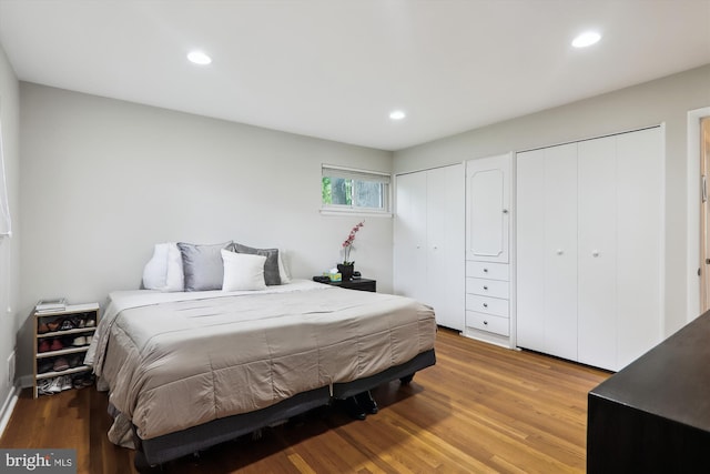 bedroom featuring two closets, recessed lighting, and light wood-style flooring