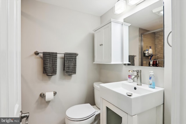 bathroom featuring toilet, vanity, and a shower with shower door