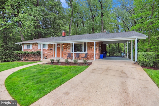 view of front facade featuring a chimney, driveway, a front yard, a carport, and brick siding