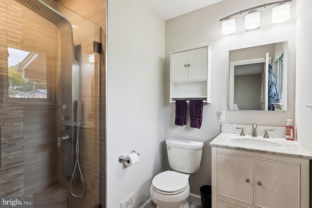 full bath featuring a tile shower, toilet, vanity, and baseboards