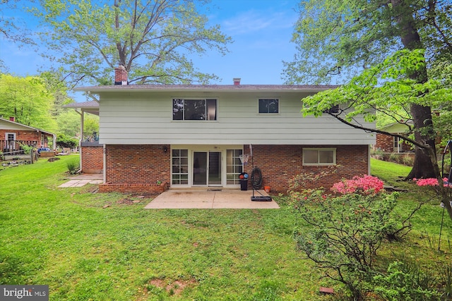 rear view of house with a patio area, a yard, brick siding, and a chimney