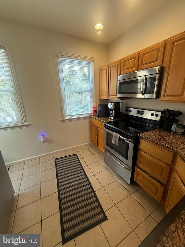 kitchen with stainless steel appliances, light tile patterned floors, baseboards, recessed lighting, and brown cabinetry