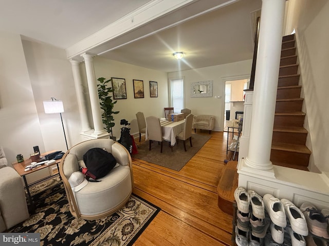 living area featuring decorative columns, light wood-style flooring, and stairway