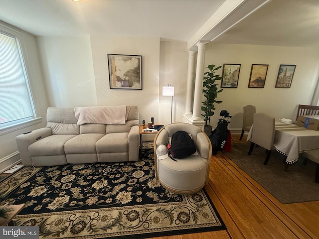 living room featuring decorative columns, wood finished floors, and baseboards