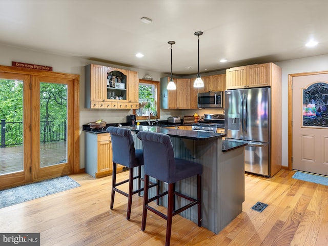 227 Haines Dr, Capon Bridge, WV 26711 - kitchen with stainless steel appliances, dark countertops, a kitchen breakfast bar, light wood finished floors, and a center island