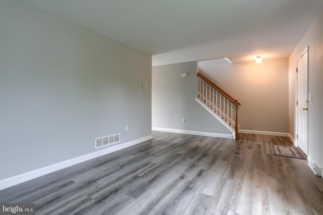 unfurnished living room featuring wood finished floors, stairs, and baseboards