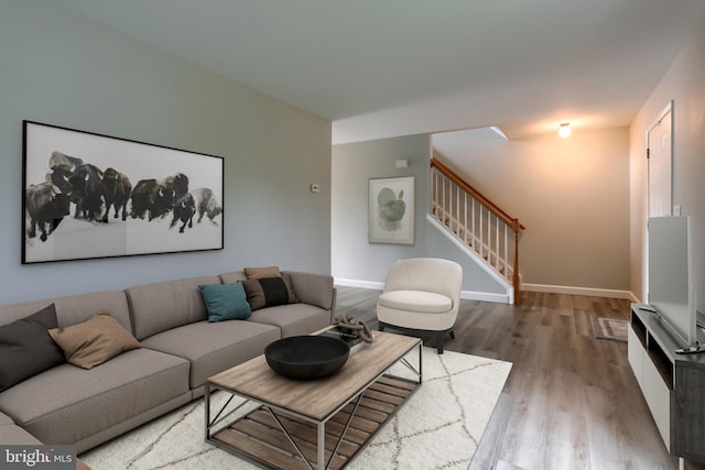 living area with wood finished floors, stairway, and baseboards