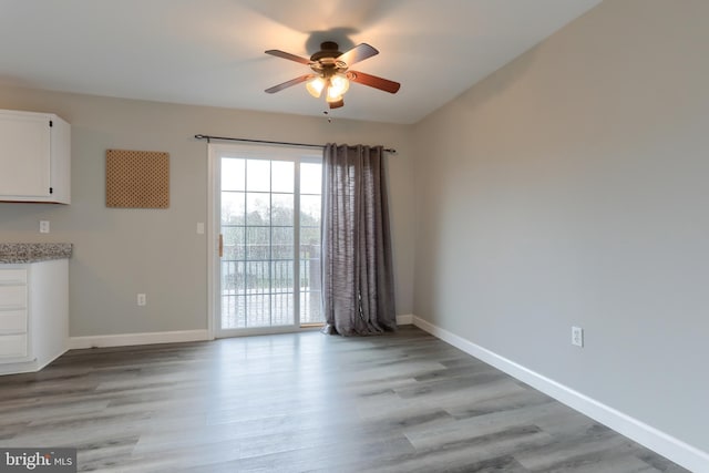 unfurnished dining area with ceiling fan, light wood-style floors, and baseboards