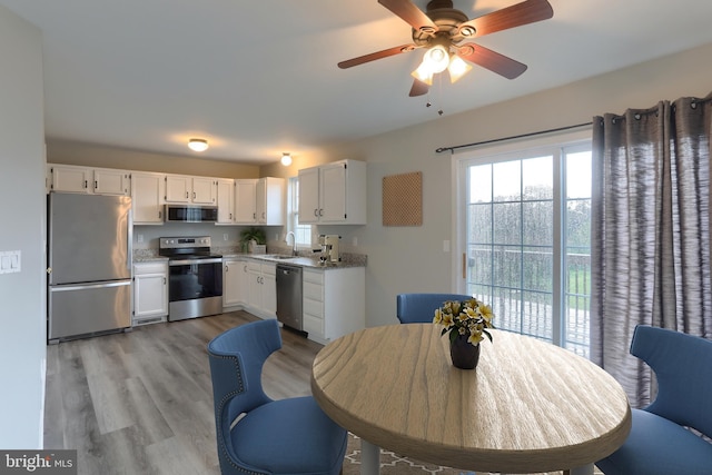 kitchen with appliances with stainless steel finishes, white cabinets, light countertops, and a sink