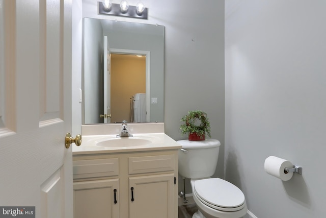 half bath with toilet, vanity, washer / dryer, and baseboards