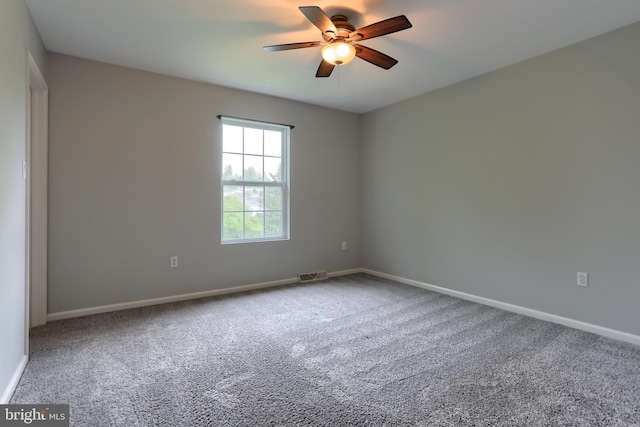 carpeted empty room with a ceiling fan and baseboards