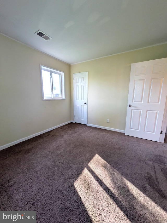 unfurnished room with baseboards and dark carpet