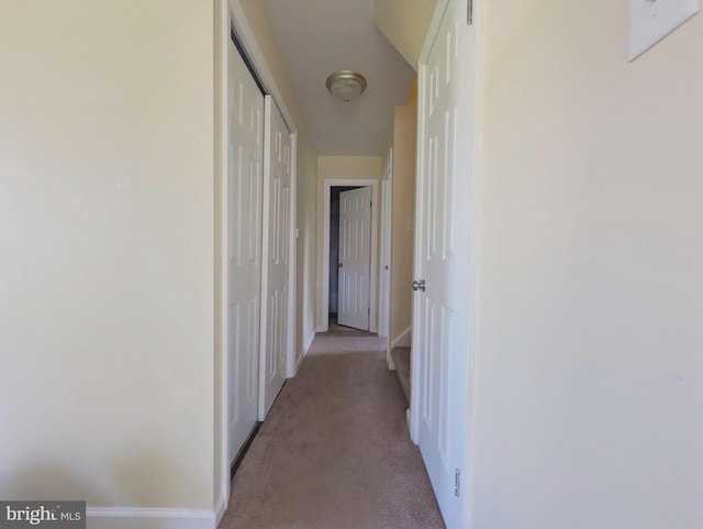hall with light colored carpet and baseboards