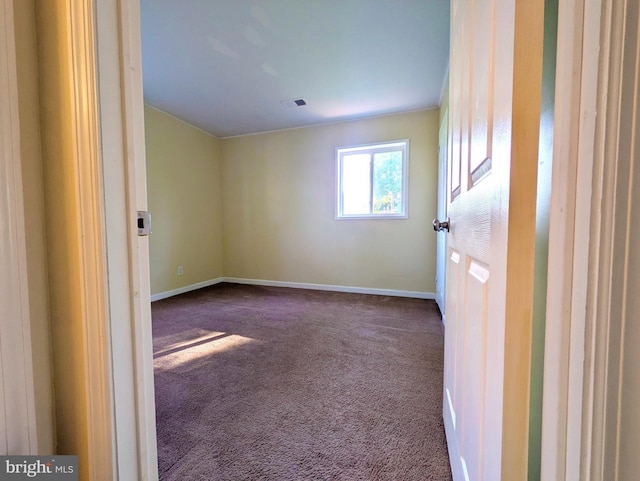 spare room featuring dark colored carpet and baseboards