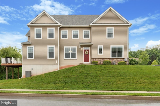 view of front of property featuring a front lawn, a wooden deck, central AC unit, and stone siding