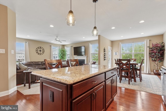 kitchen with open floor plan, wood-type flooring, a fireplace, decorative light fixtures, and recessed lighting