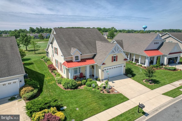 view of front of house featuring a porch, concrete driveway, a front lawn, and a residential view
