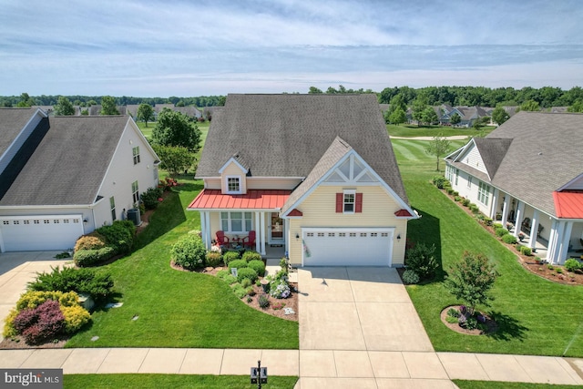 traditional-style house with a porch, driveway, a standing seam roof, and a front yard