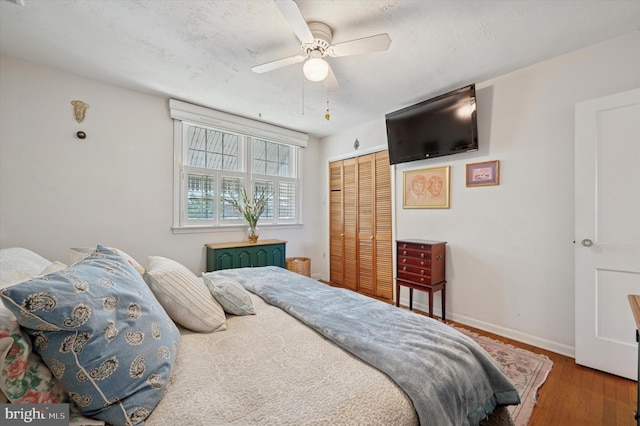 bedroom featuring wood finished floors, a closet, baseboards, ceiling fan, and a textured ceiling