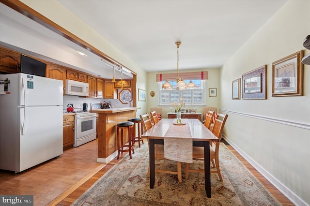 dining space featuring light wood-type flooring, a chandelier, and baseboards