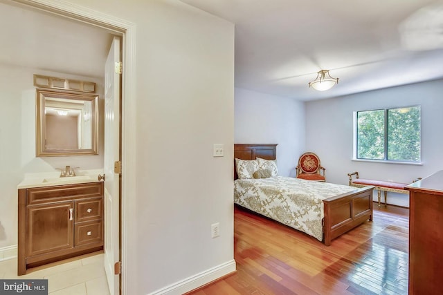 bedroom with a sink, light wood-style flooring, and baseboards