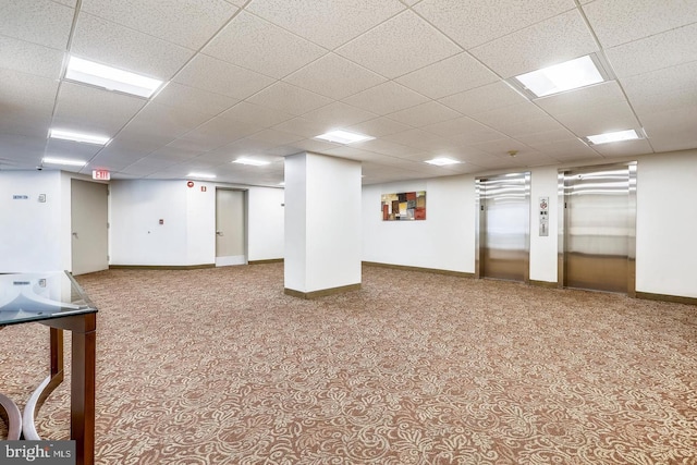 finished basement with elevator, a drop ceiling, baseboards, and carpet floors