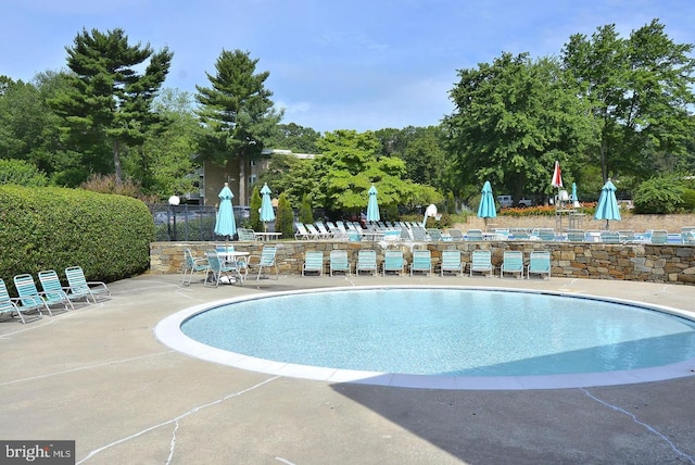 community pool with a patio area and view of scattered trees